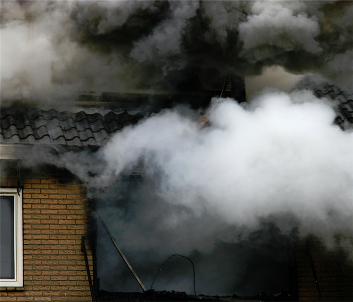 smoke billowing out of the windows of a house on fire