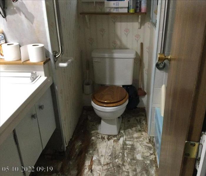 A bathroom with sewage and debris covering the floor